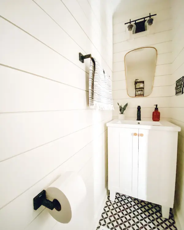 The light fixture with glass clear shades hung high and no door mat make this small half bathroom look larger.