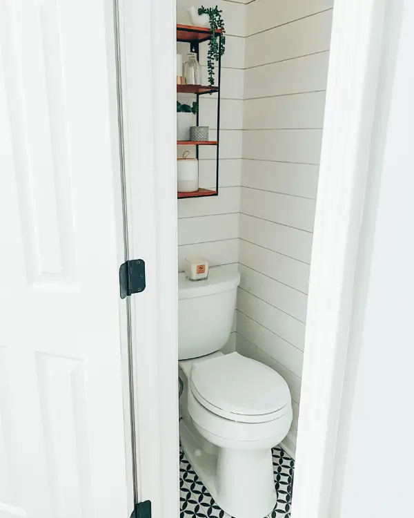 The same grout color as the tiles and white shiplap make this small half bathroom look larger.