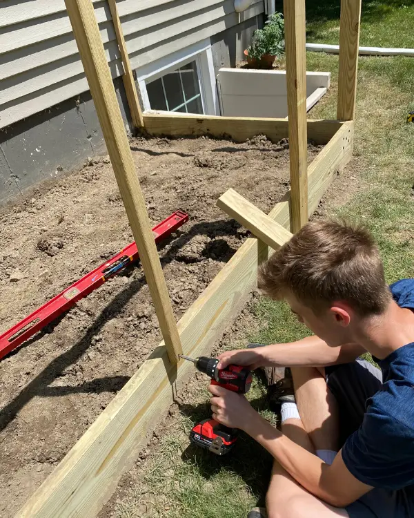 Drilling in the screws to attach the balusters to the garden fence