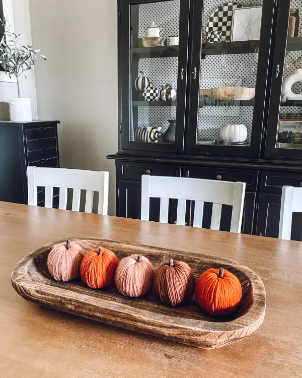 A row of yarn pumpkins in a dough bowl is a cute fall centerpiece idea.