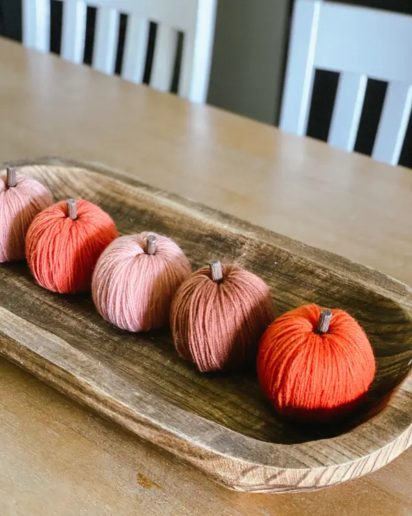row of yarn pumpkins in a dough bowl