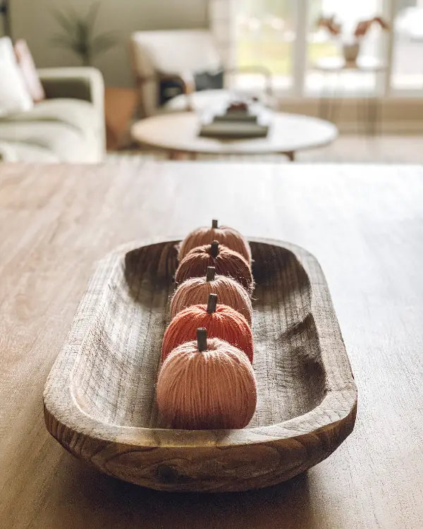 A row of pumpkins in a dough bowl is a fall cnterpiece idea.