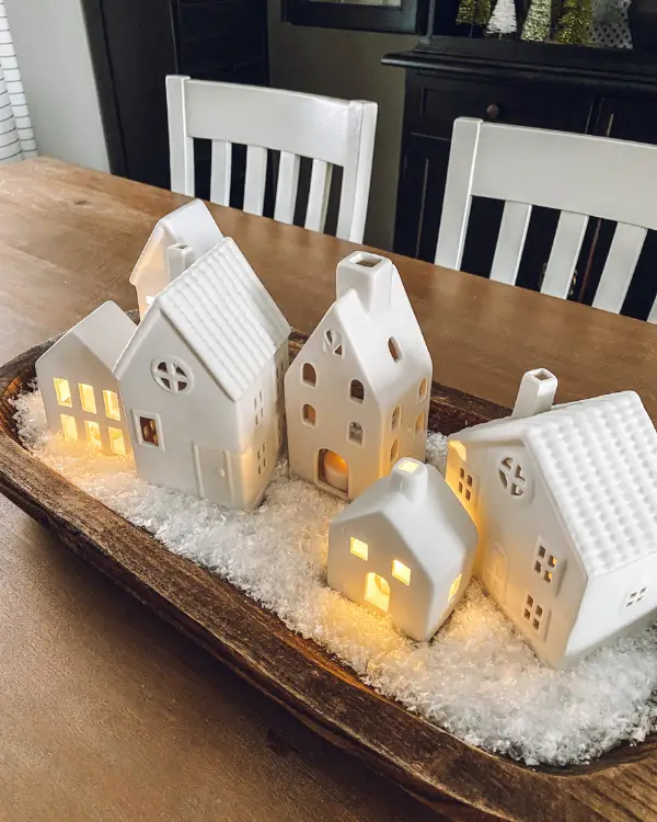 Lit up white ceramic houses in the snow in a dough bowl