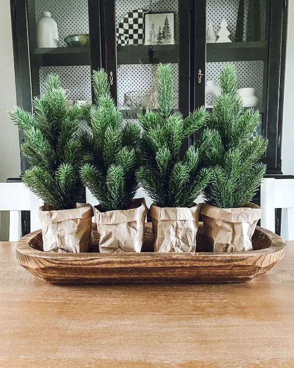Christmas trees in brown paper bags lines up in a dough bowl