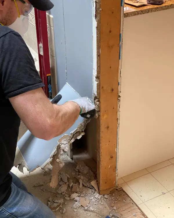 Tearing out pieces to prepare the opening for drywall