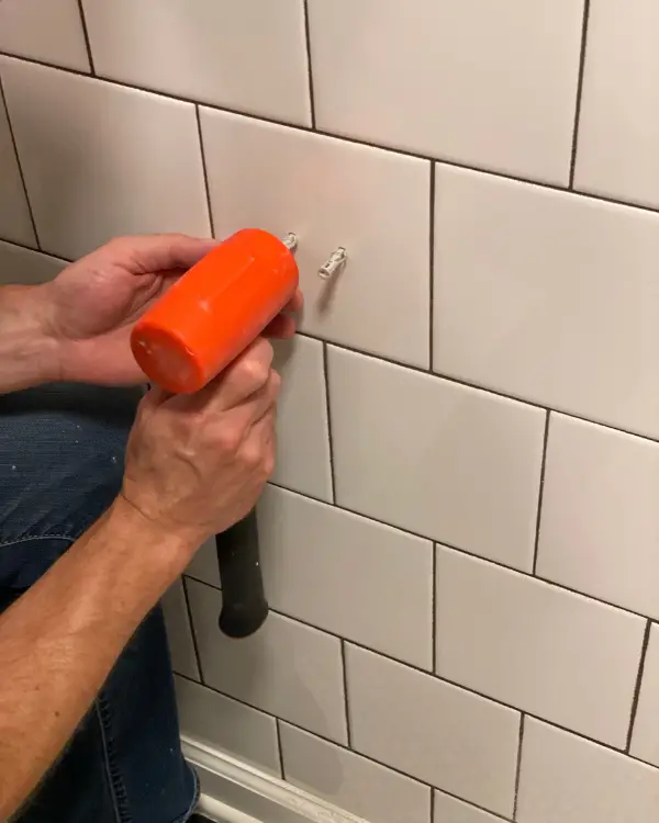 after drilling holes into tiles, getting ready to hang the toilet paper holder
