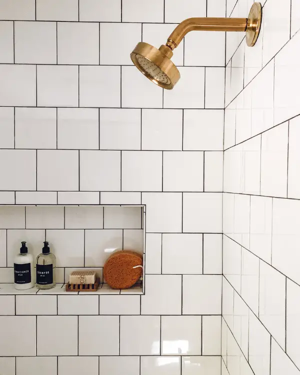 Gold shower fixtures and square white tiles as part of this bathroom makeover