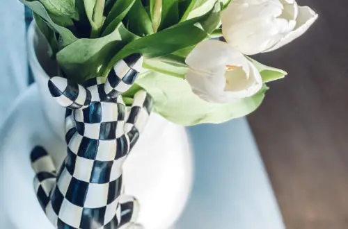 checkered bunny hanging on a white vase of white tulips for spring and Easter