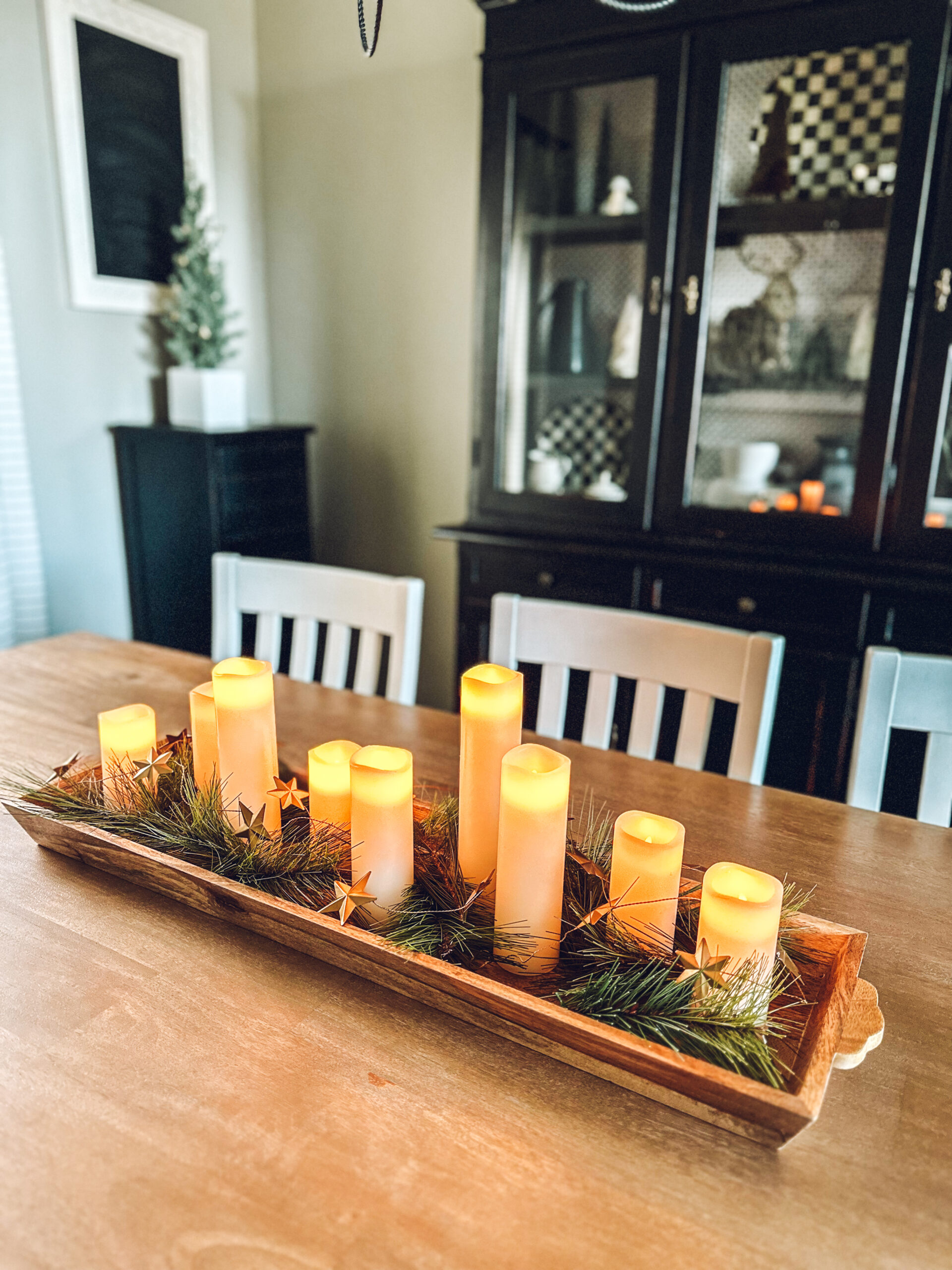 flameless candles, greenery and gold star garland on a long tray on the table