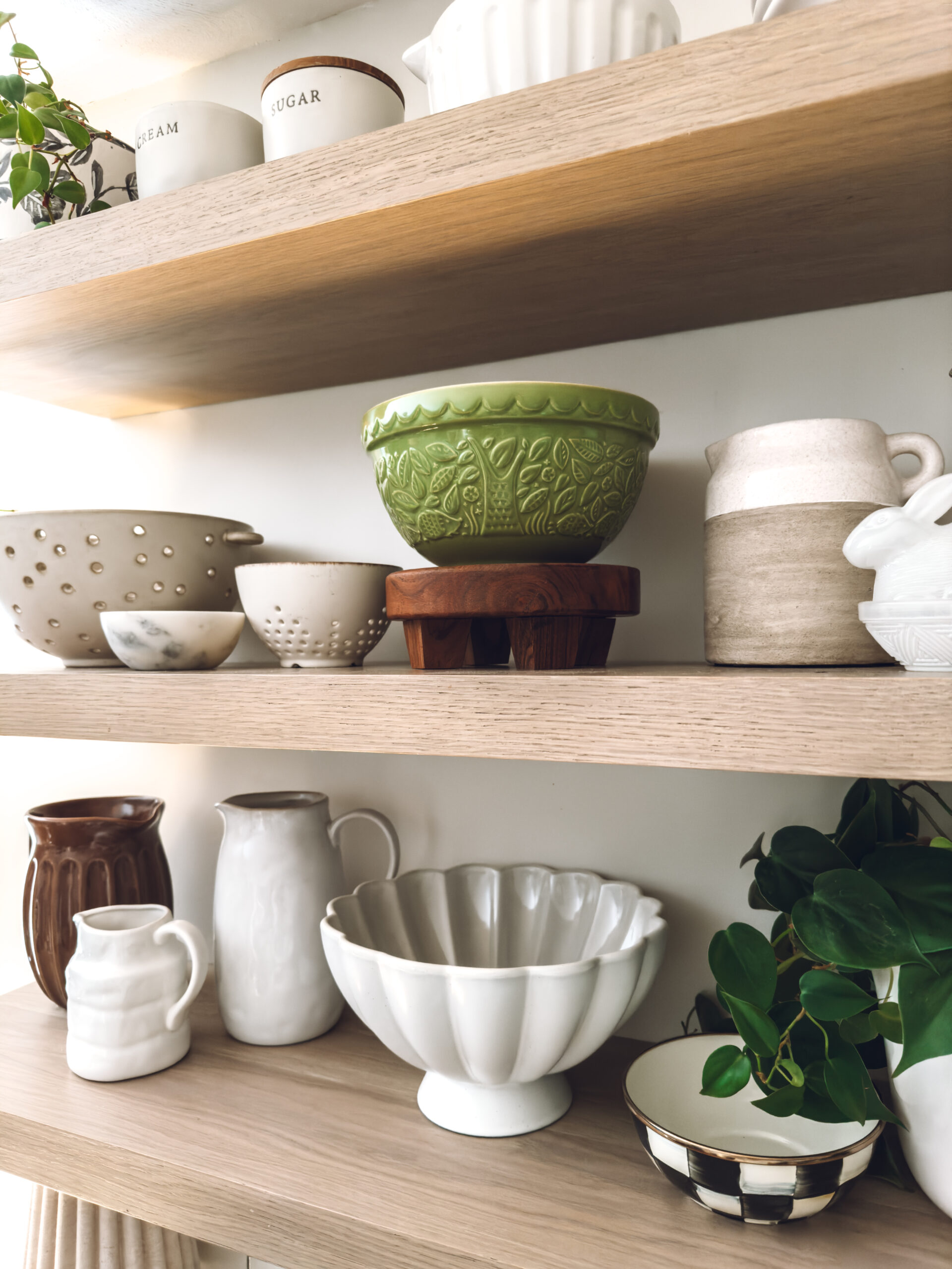 My green Mason Cash bowl on a shelf in the kitchen surrounded by neutral decor.