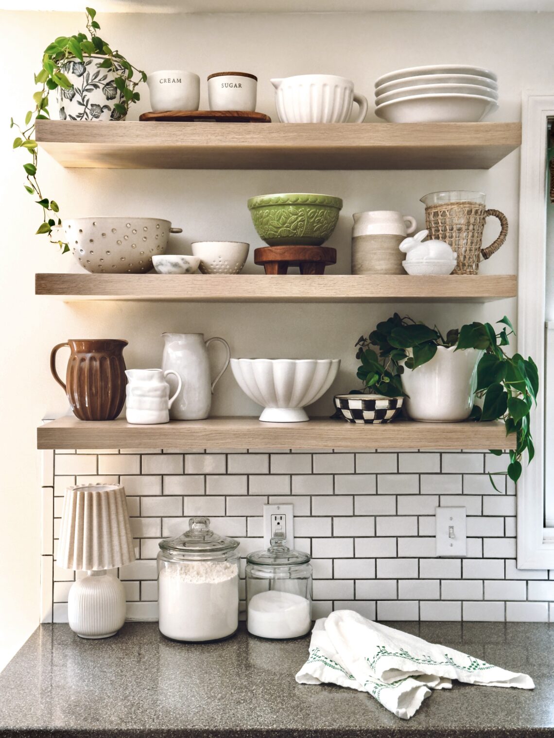 The green Mason Cash bowl on kitchen shelving containing neutral decor adds color to the kitchen