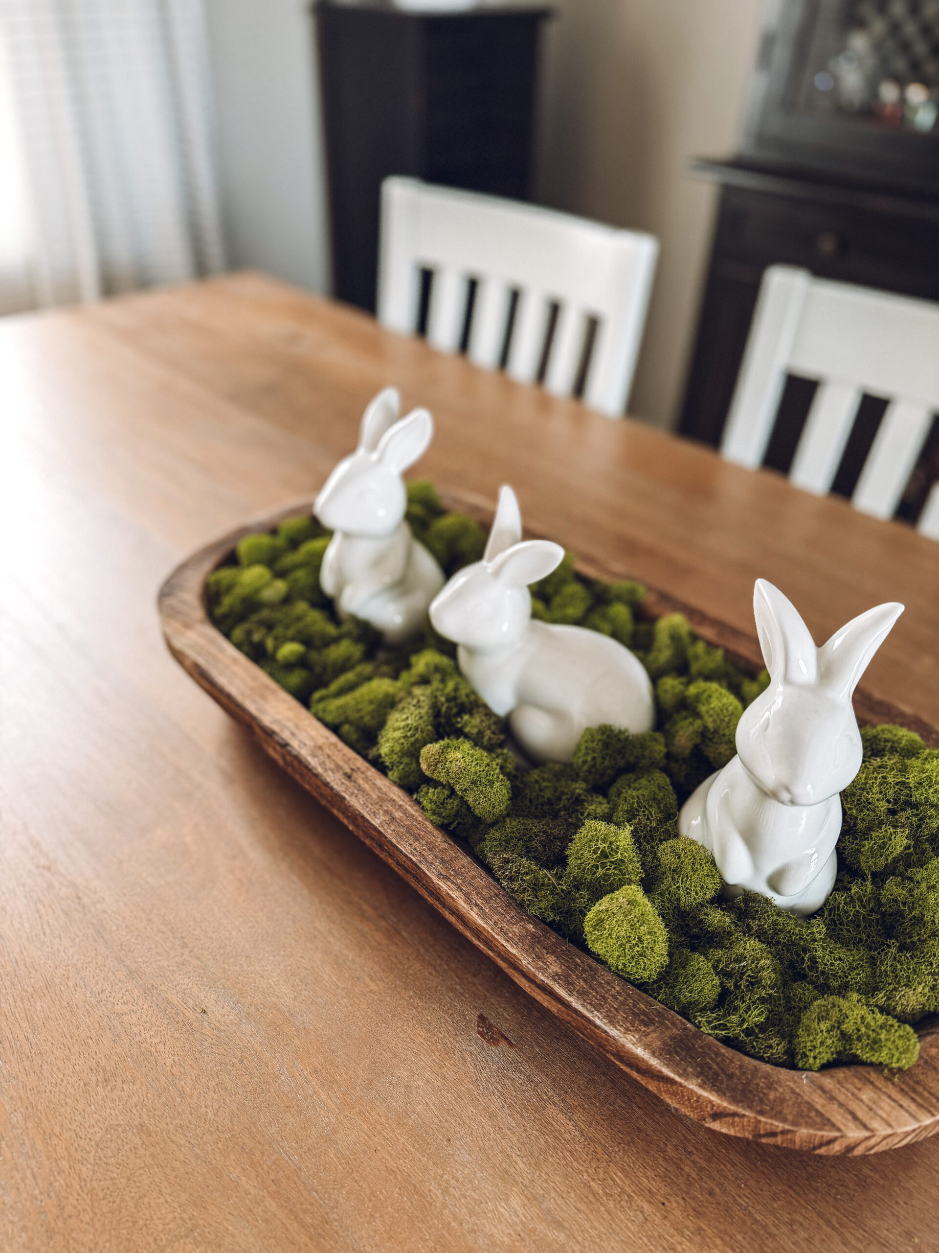 3 ceramic white bunnies nestled in green moss